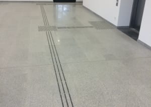Barrierefreier Flurbereich mit Naturstein und taktilen Leitlinien